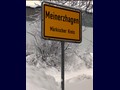 Ein Ortseingangsschild versinkt im hohen Schnee